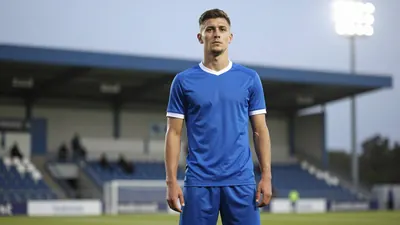 A photorealistic image of a Barrow player in a blue kit, with a white shirt and blue shorts, standing in front of a...
