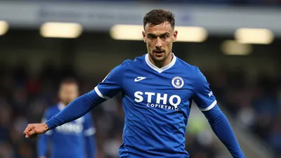 A mid-30s Barrow midfielder in a solid blue kit, waist-up, focused expression, tight action crop as he prepares to strike...