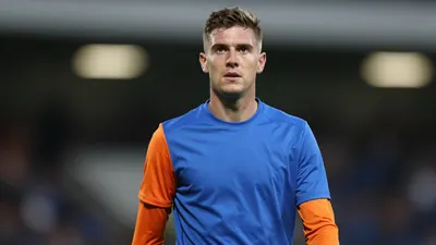 Mid-30s Barrow midfielder, athletic build, waist-up, wearing a plain blue shirt with orange sleeves, soft cotton texture...