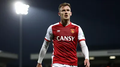 A photograph of a Barrow FC player in action, wearing their home kit, taken in sharp focus with a shallow depth of field