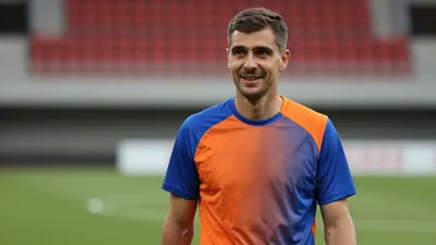 Mid-30s male community coach, athletic build, waist-up, wearing a plain unmarked training top split blue and orange, soft...