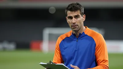 Mid-30s male coach, athletic build, waist-up, intense expression, short dark hair, slight stubble, eyes focused forward;