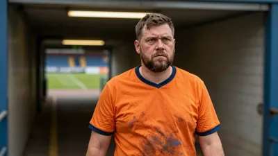 A 35-year-old, stocky, bearded shipyard worker in a faded orange Barrow training top, its blue fabric slightly worn...