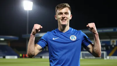 A 24-year-old forward in a blue kit, celebrating his signing with Barrow AFC