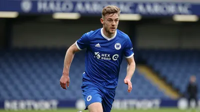 A Barrow AFC player in a blue kit sprinting with the ball at the Halo Aerospace Stadium